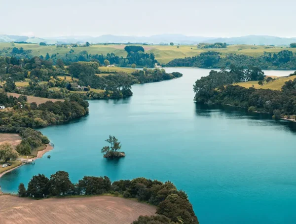 Aerial view of a pristine river flowing through lush green farmland and forest, showcasing clean water and sustainable land use, ideal for promoting water quality monitoring and environmental conservation technology.