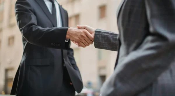 Two businessmen in suits shaking hands making a business deal