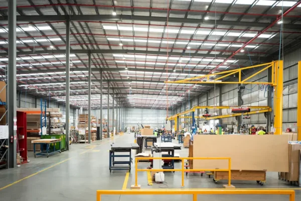 Large, well-lit warehouse interior with machinery, workstations, shelves, and equipment scattered throughout the open industrial space.